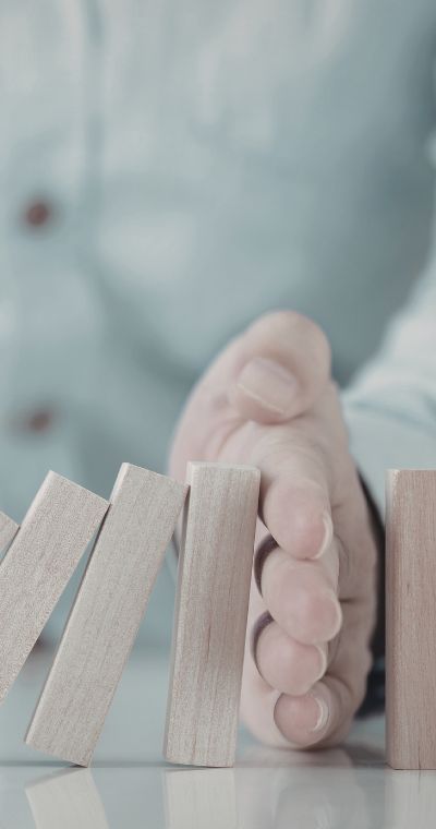 Hand hält fallende Dominosteine auf